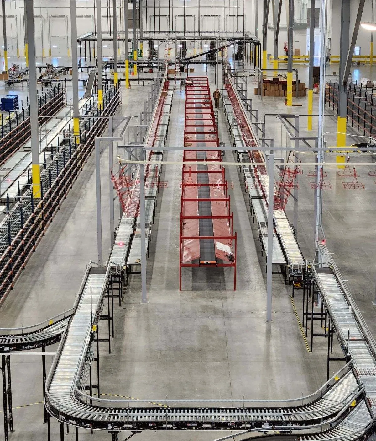 Wide aerial view of a large distribution center with extensive red conveyor and sortation systems