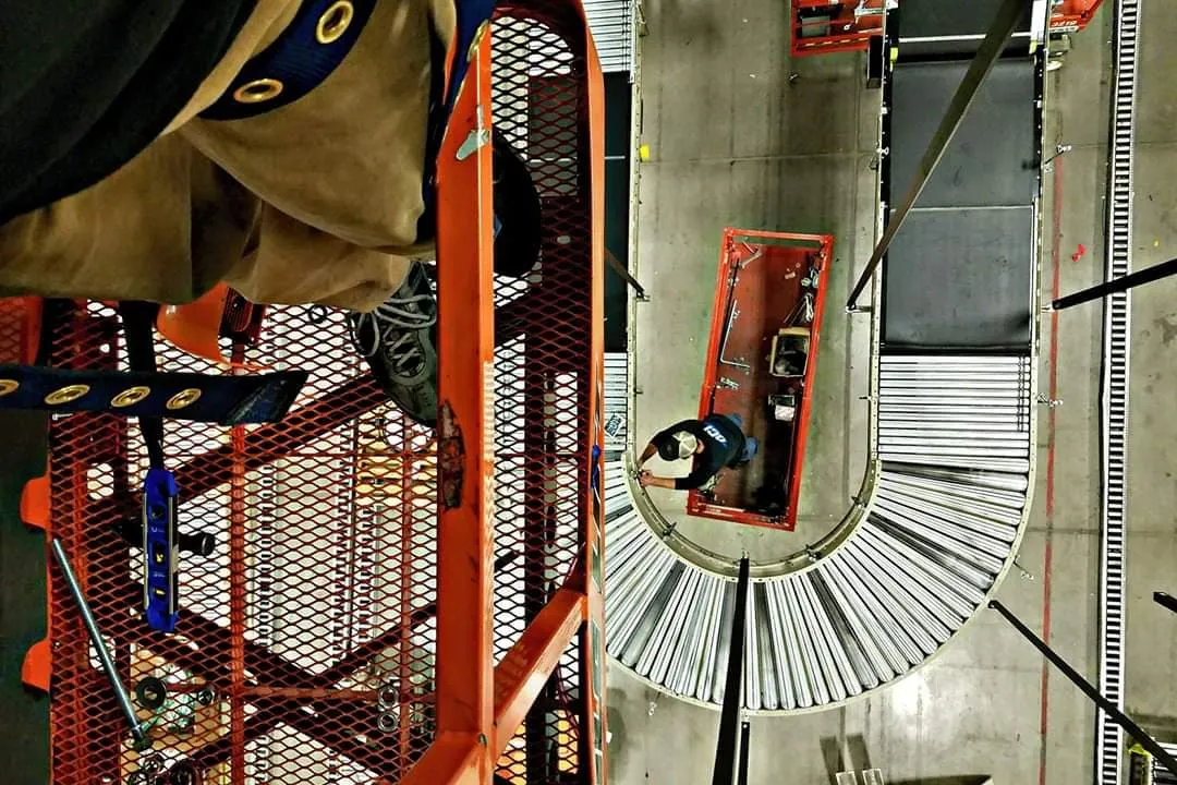 Close-up view of roller conveyor with technician working from a scissor lift below