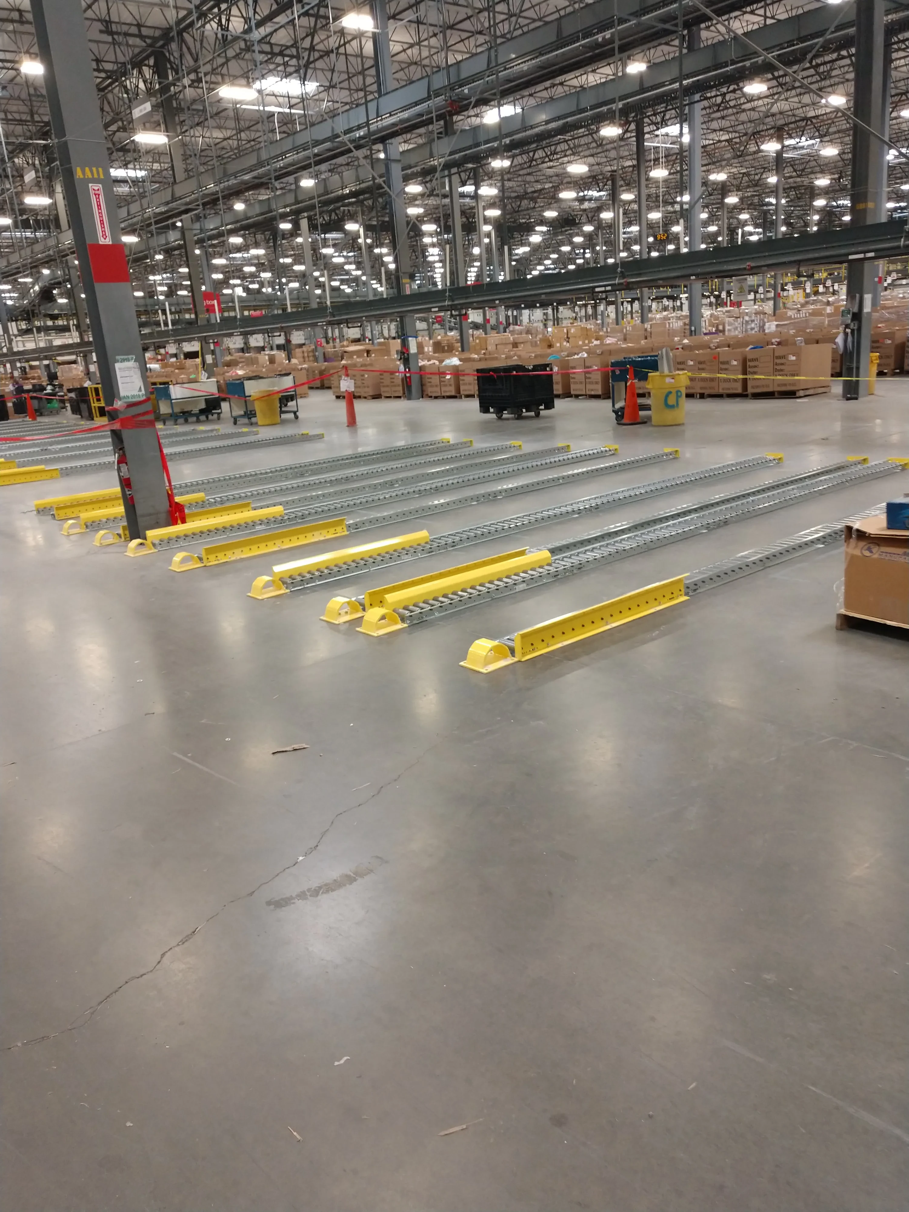 Long rows of gravity roller conveyor sections staged for installation in a large warehouse