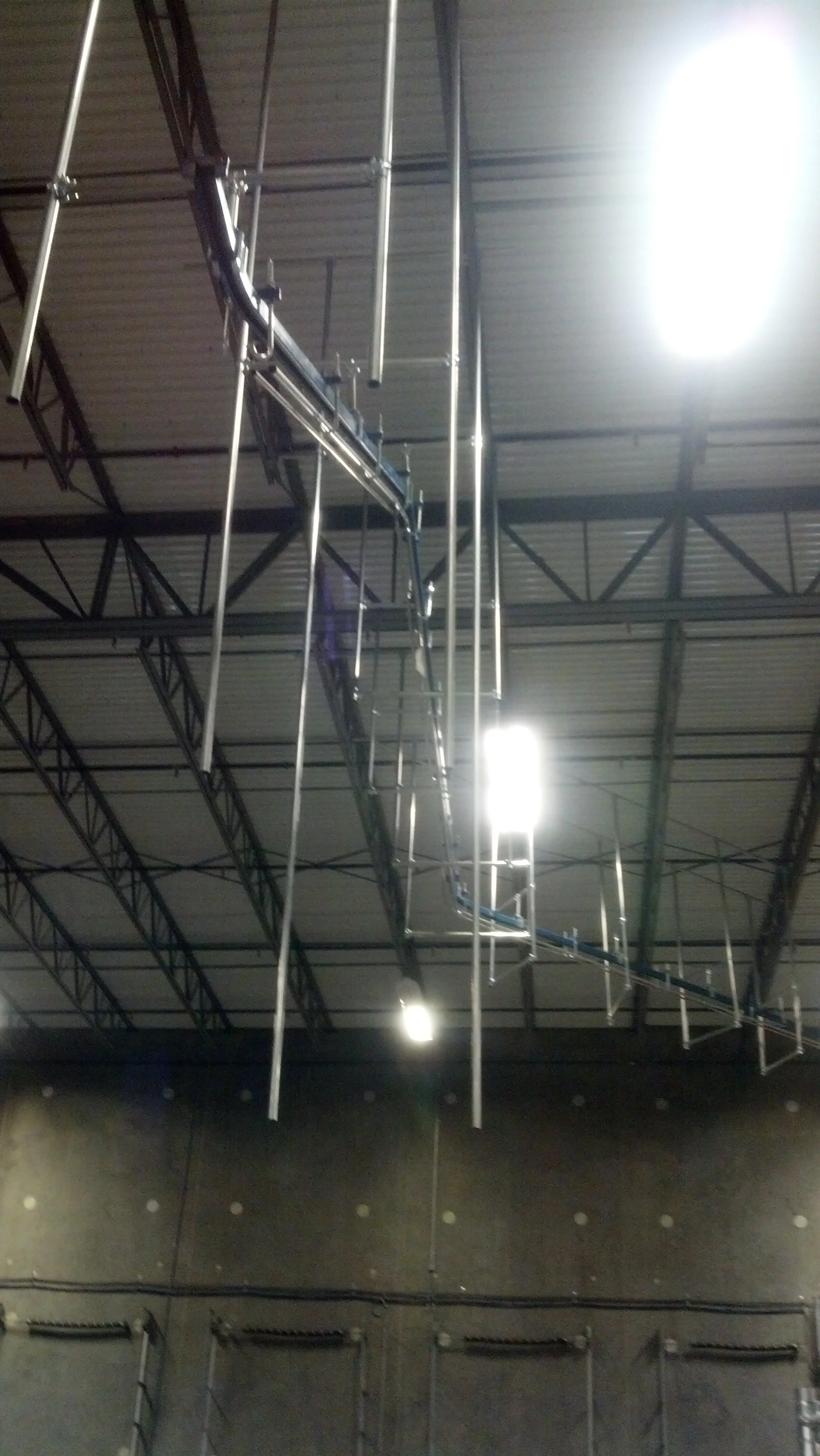 Complex overhead conveyor system with multiple vertical drops and hanging carriers inside a large distribution center