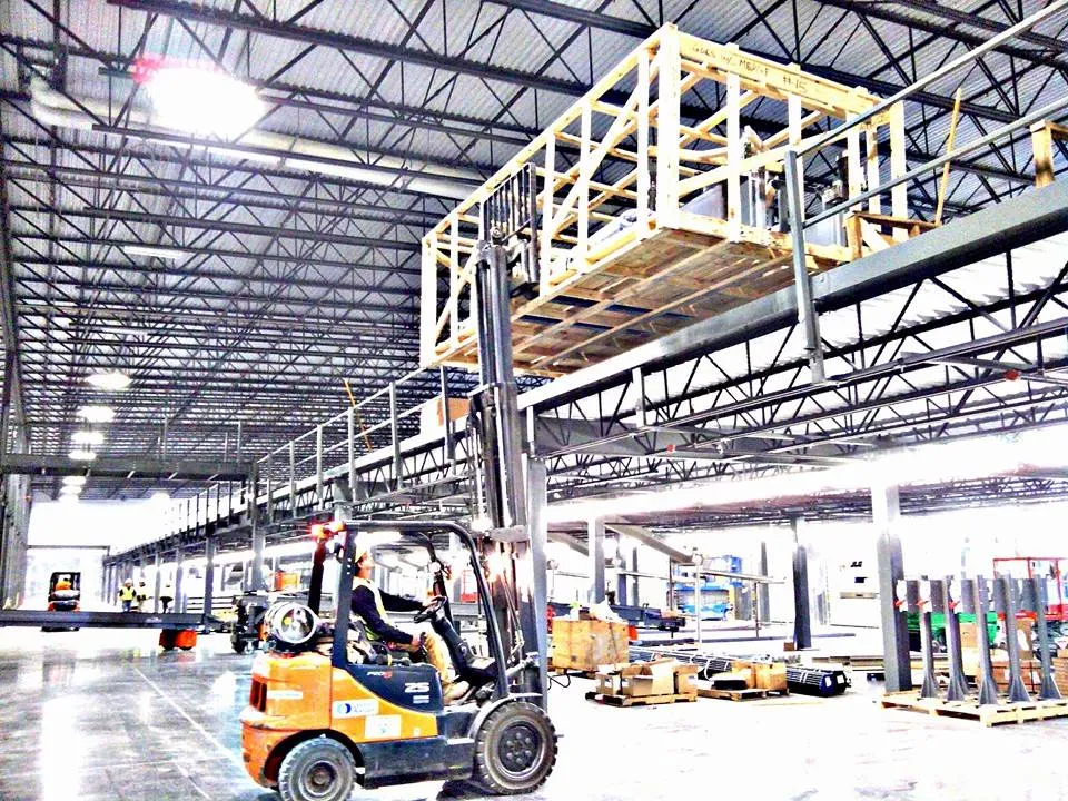 Forklift operating beneath a large elevated conveyor structure during installation