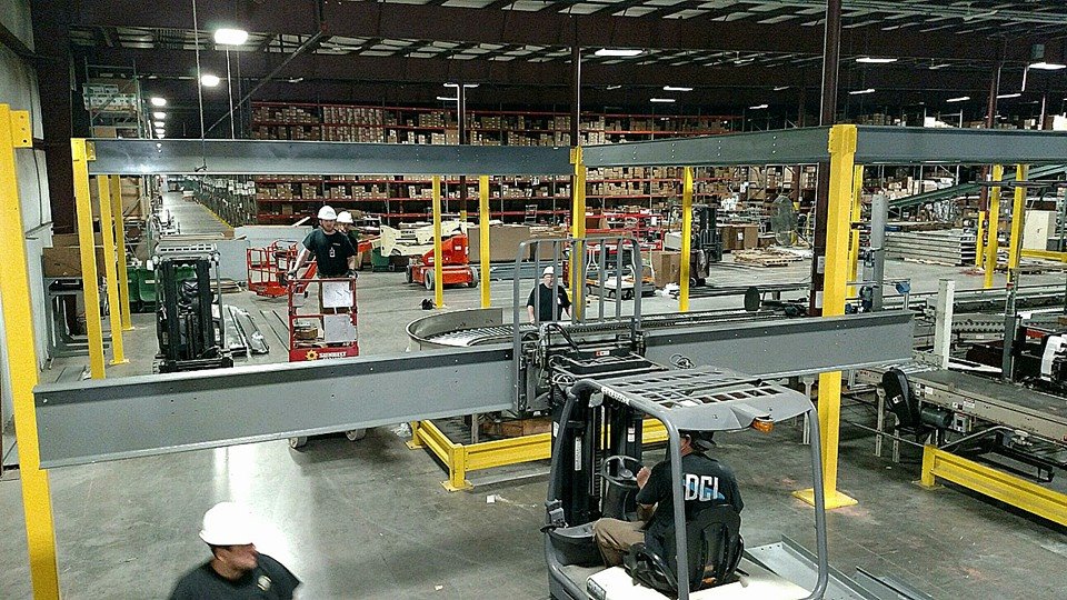 Worker performing maintenance on an overhead conveyor from a scissor lift